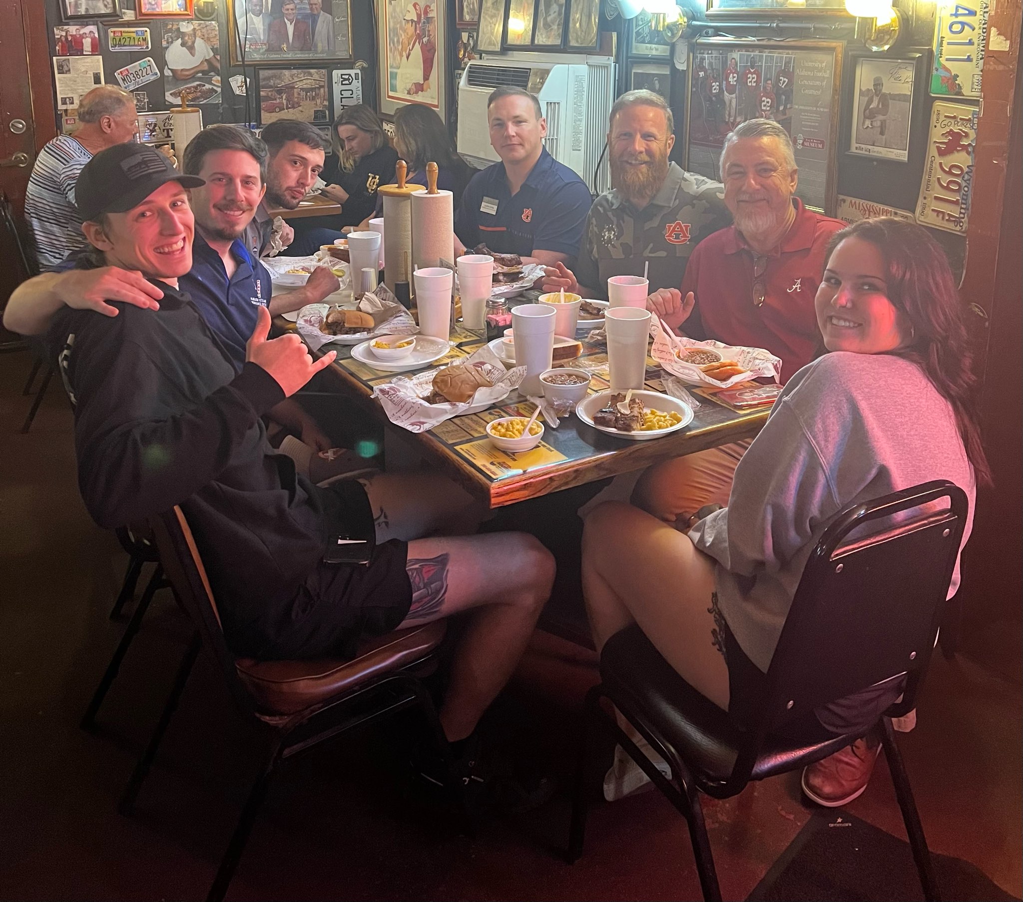 A group of people sitting at a restaurant table full of food and drinks.
